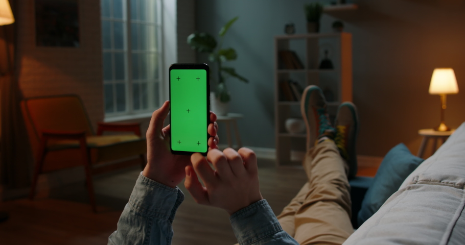 Close up shot of guy relaxing on couch at night, using smartphone with chroma key green screen and doing various gestures on display - technology, communications concept 4k template | Shutterstock HD Video #1061053939