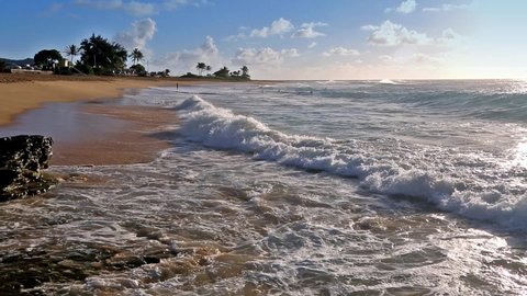 Waves crashing on Sandy beach with an unidentified people on Oahu, Hawaii, USA