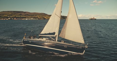 Yacht sailing on open sea at windy day aerial. Sun shine over white sail boat at ocean bay. Sailboat cruise at serene seascape. Amazing ship racing at summer sunny day. Cinematic drone shot