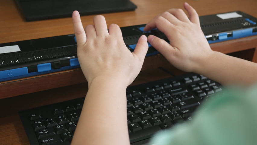 Close-up blind person woman hands using computer keyboard and braille display or braille terminal a technology assistive device for persons with visual disabilities. | Shutterstock HD Video #1061062117