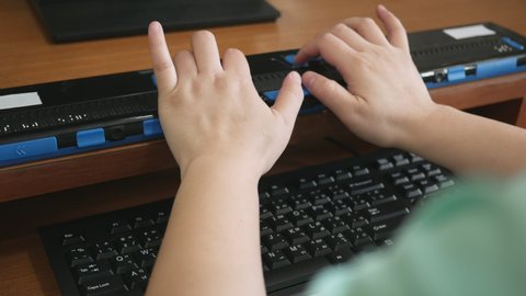 Close-up blind person woman hands using computer keyboard and braille display or braille terminal a technology assistive device for persons with visual disabilities.