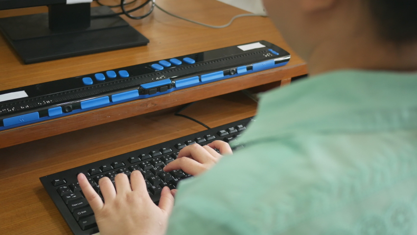 Rear view of blind person woman using computer keyboard and braille display or braille terminal a technology assistive device for persons with visual disabilities. Royalty-Free Stock Footage #1061062123