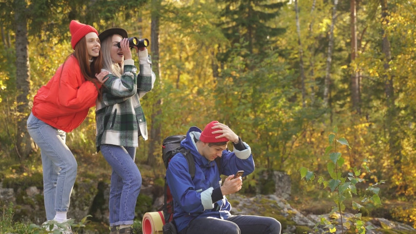 Carefree travellers enhoy the beauty of nature on mountains, they travel on the rocky terrain on a sunny autumn day, take photo on smartphone and use binoculars. | Shutterstock HD Video #1061067436
