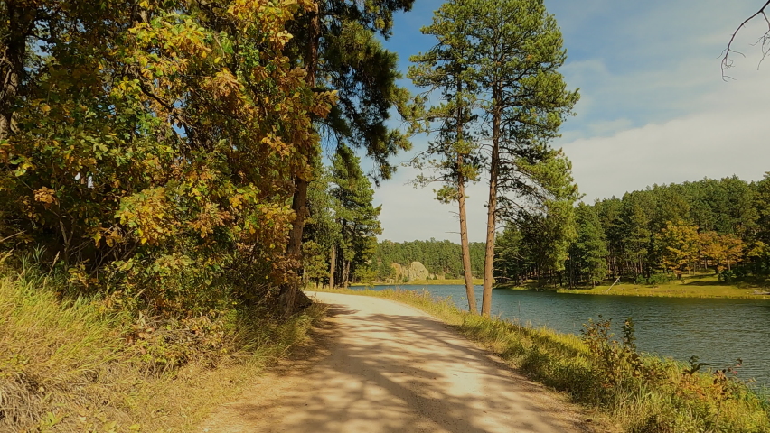 South Dakota Black Hills trail along lake Autumn POV pull back 4K. Black Hills of South Dakota. Mountain, valley, landscape scenic discovery. State Park, wildlife, lakes, campgrounds, picnic areas.