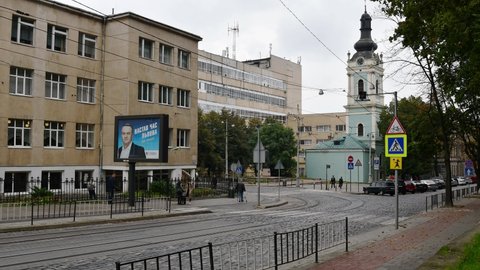 Lviv, Ukraine - 10 09 2020: Busy city street time lapse. Car traffic and people walking by pedestrian crossing over road with political ads billboard nearby. Local elections in Ukraine