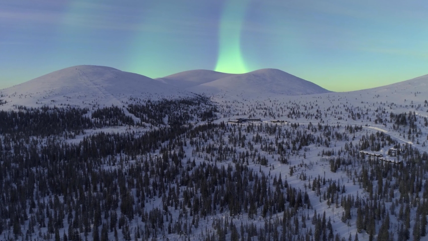 Aerial, drone shot towards Aurora Borealis, the Northern lights above the Pallastunturit mountains, in Pallas-yllastunturi national park, winter dawn, in Muonio, Lapland, Finland | Shutterstock HD Video #1061069929