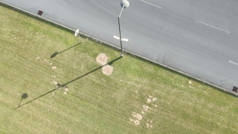 Aerial top down view of an isolated street lamp post with cameras installed for surveillance, beside vacant road.