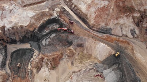 Iron ore quarry open pit mining. Aerial view of excavators and machinery are loading ore into dump truck in quarry. Large industrial quarry
