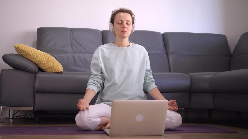 Coronavirus lockdown restrictions. Front view of Caucasian woman practicing guided meditation at home online. Royalty-Free Stock Footage #1061074393