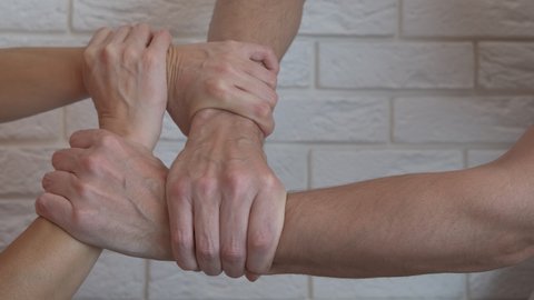 Family hold each other's hands. A woman and a man hold each other's hands in the room.