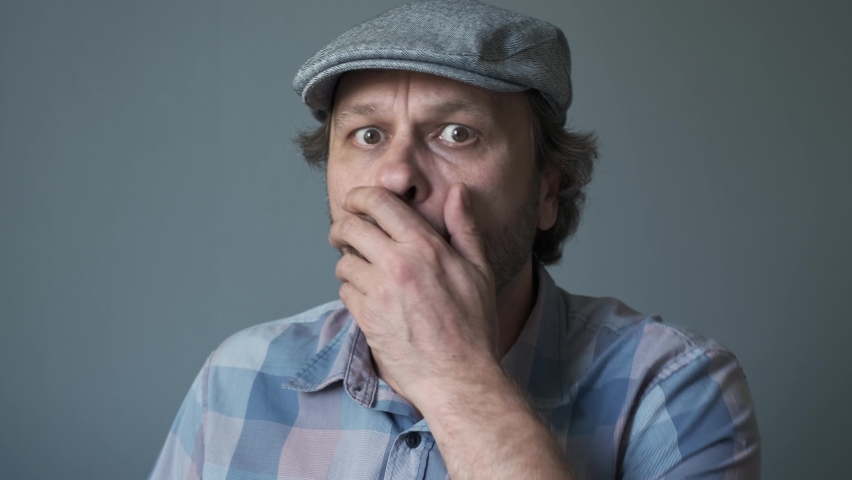 A curious funny surprised Middle-aged  man who is looking at the camera. Humorous portrait of a man with no cut hair in cap. | Shutterstock HD Video #1061080699