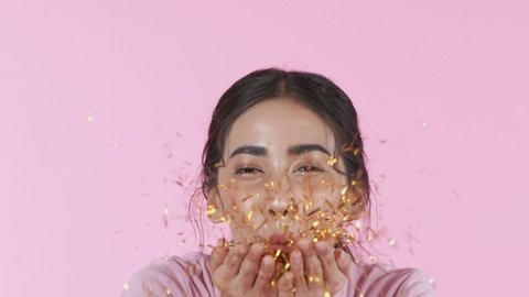 Beauty concept. The girl is blowing the glitter on the pink background. 4k Resolution.