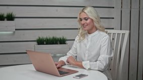 Blond woman freelancer works at a laptop at home. Young woman conference calling on laptop talks with online teacher studying. Distance learning. Work from home concept.