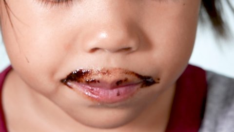 Closeup view of cute little girl eating sweet donuts and enjoying the taste over white background.