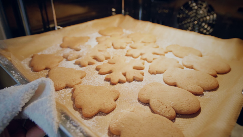 The process of baking a traditional Christmas gingerbread cookie. Remove hot biscuits from the oven. Concept Christmas | Shutterstock HD Video #1061086240