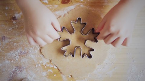 Close-up top view of a child's hand making a gingerbread cookie in the form of a snowflake. Christmas and New Year concept