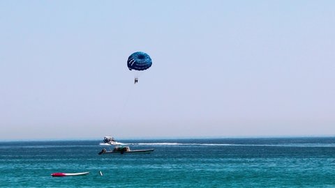 Parasailing at Fujairah in United Arab Emirates, extreme Sport. Tourists para sailing - popular entertainment for holiday travelers on Fujairah Beach UAE. Concept of vacation fun.