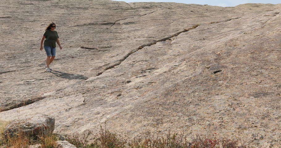 Woman hiking off Independence Rock historical site Wyoming 4K. Pioneer names carved in rock. Historic pioneer site Landmark along Oregon, California and Mormon Trails.