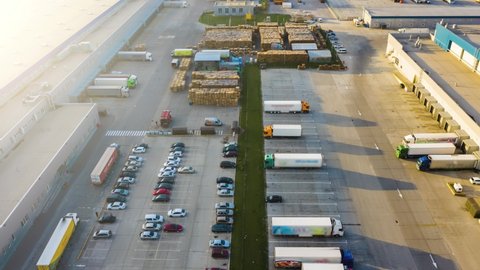 Logistics park with a warehouse - loading hub. Semi-trucks with freight trailers standing at the ramps for loading/unloading goods. Aerial hyper lapse - motion time lapse