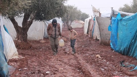 A father and son walk in the mud among the refugee tents.
Walking on mud. Refugees in the Middle East.
Aleppo, Syria 16 Jun 2019