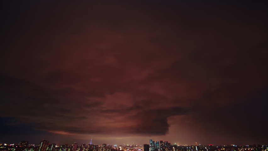 Amazing timelapse of the night storm over the big city, with colorful clouds moving on the sky and bringing first drops of rain, and bright lightnings illuminating the scene. Royalty-Free Stock Footage #1061106421