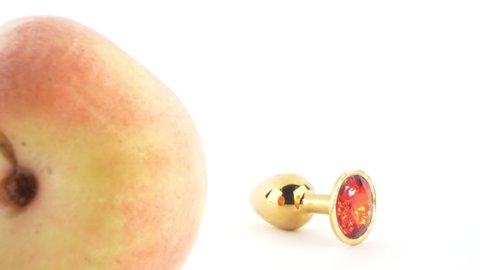 close-up. ripe peach and jewelry butt plug nearby. White background. copy space.