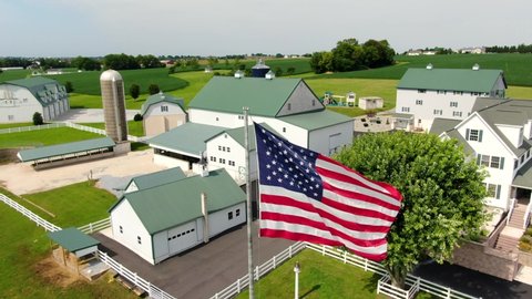 Dramatic rural farm scene in United States of America, USA. Pristine green and white buildings set among green rolling fields, aerial drone view.