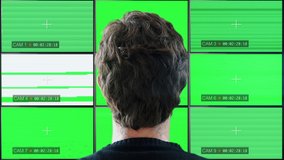 Watching Multiscreen Monitors Green Screen TV static. Headshot of a man watching recorded cameras on a multiscreen wall with TV static