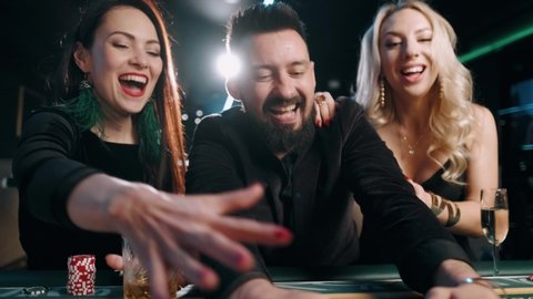 Two young women and bearded man are winning and rejoice in victory at the casino