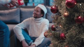 Christmas tree near african american couple with cups on blurred background