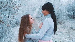 Beautiful woman mother gently touches stroking hair cute charming little girl daughter. Backdrop winter frosty snowy forest nature. Concept family happy. Same outfit blue sweate, pink long skirt dress