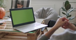 View over head on of caucasian woman holding pc notebook computer with green screen while watching something and working from home. Chroma key. 4k video footage slow motion