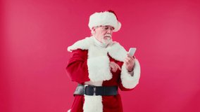 happy santa claus showing smartphone with green screen isolated on red