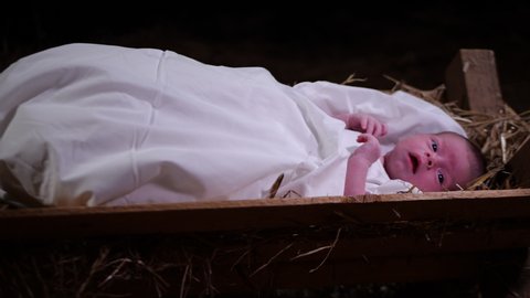 4K Dolly: Baby Jesus laying in a Manger with straw and Hay. Christmas Nativity Scene in the stable. Close