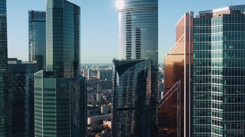 Moscow city glass skyscrapers drone zoom in close to the buildings. Famous Moscow International Business Center sunny evening time, blue horizon line on the background