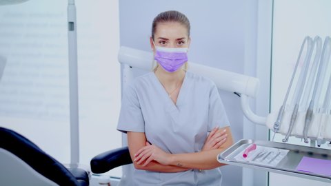 Close Up Portrait of Young Female Dentist In Surgical Mask Satisfied With Her Job Sitting In Modern Clinic Closeup Looking Straight To The Camera. Concept of Medicine, Health Care and People Slow Mo