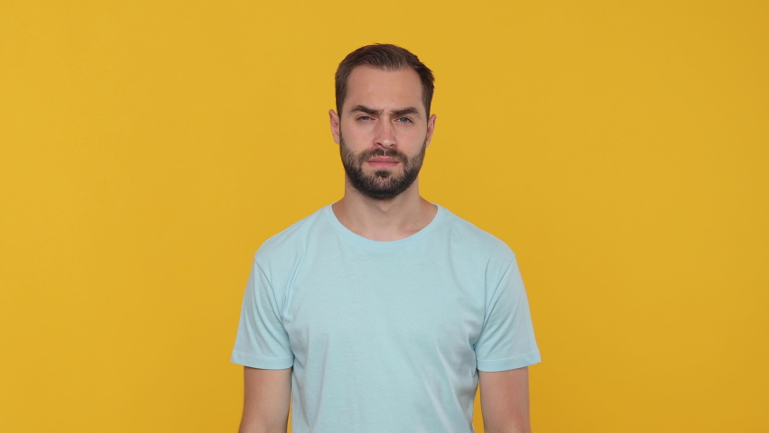Bearded young man 20s in basic casual blue t-shirt isolated on yellow background studio. People emotions lifestyle concept. Looking camera rubbing fingers showing cash gesture asking for give me money Royalty-Free Stock Footage #1061130004