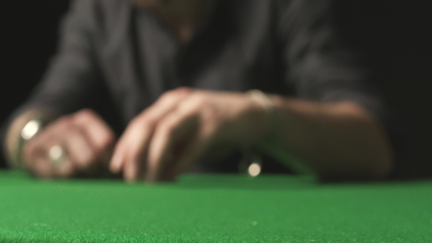 Slow motion of a male hand betting with red chips on the green poker table in casino. Close-up. Royalty-Free Stock Footage #1061135542