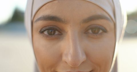Close up of face of young muslim beautiful woman in traditional headscarf smiling happily to camera. Portrait of pretty Arabian female at street. Outdoors. Islamic girl. Charming eyes.