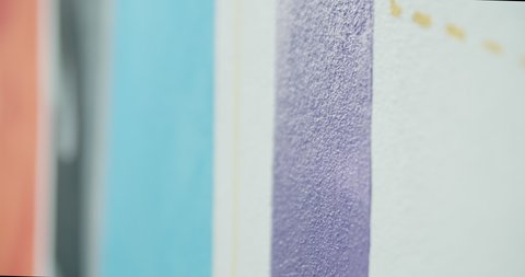 Side view of painting a mural on a wall with brush and roller and palette. Close up, slow motion.