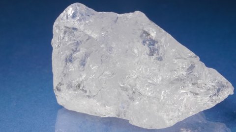 Mineral rock crystal on a blue background. Colorless quartz close-up view.