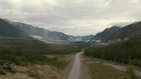 Picturesque View of Scenic Road from Above alongside Winding Glacial River. Aerial Drone Shot. Alaska Highway in the Northern Rockies, British Columbia, Canada.