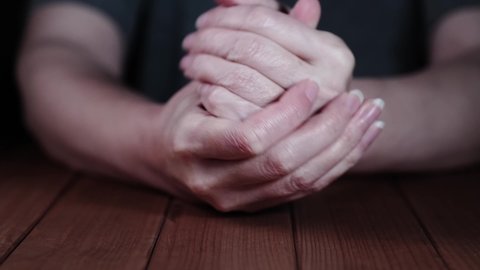 nervous woman squeezes her hands on the table. Close-up of hands.