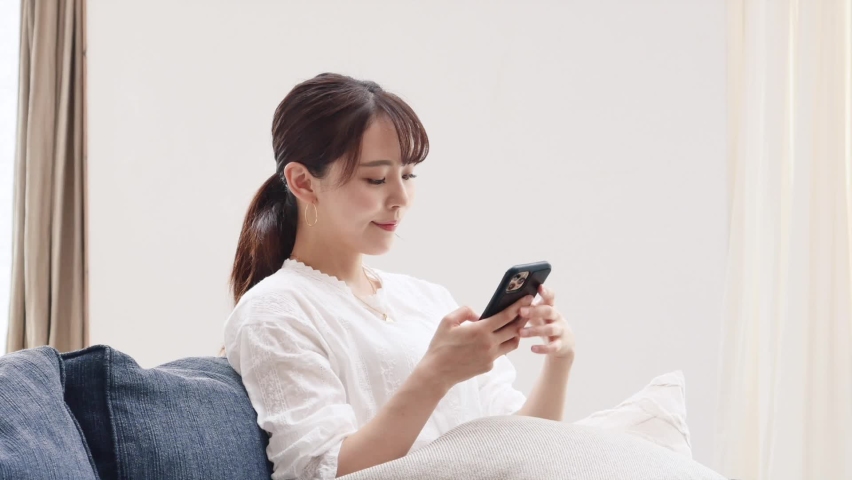 Asian woman using the smart phone on the sofa Royalty-Free Stock Footage #1061147566