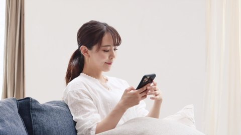 Asian woman using the smart phone on the sofa