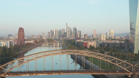 Frankfurt am Main, Germany Skyscraper Skyline View slow Dolly out revealing Bridge over Main River at Sunrise, Aerial backwards