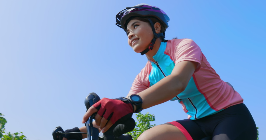Slow motion of asian young woman wear helmet riding a bicycle on the road and take look at watch to count her time Royalty-Free Stock Footage #1061153308