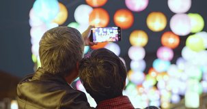 Asian elder couple visit lantern fesitival at night and take a video happily during chinese new year