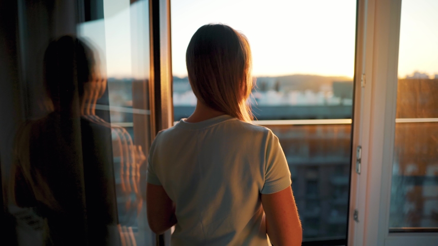 Woman with a cup of coffee or tea goes to the balcony to admire the sunset Royalty-Free Stock Footage #1061154595