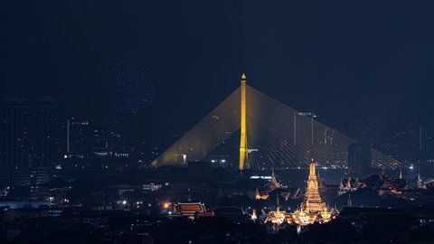 Time lapse of Drone show about The King rama 9, Bhumibol Adulyadej in memorial, at Rama 8 Bridge and Temple of Dawn or Wat Arun, Urban town city, Bangkok skyline. downtown area, Thailand at night.